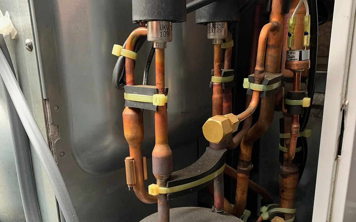 Intérieur d'une unité extérieure : compresseur et circuit frigorifique en cuivre