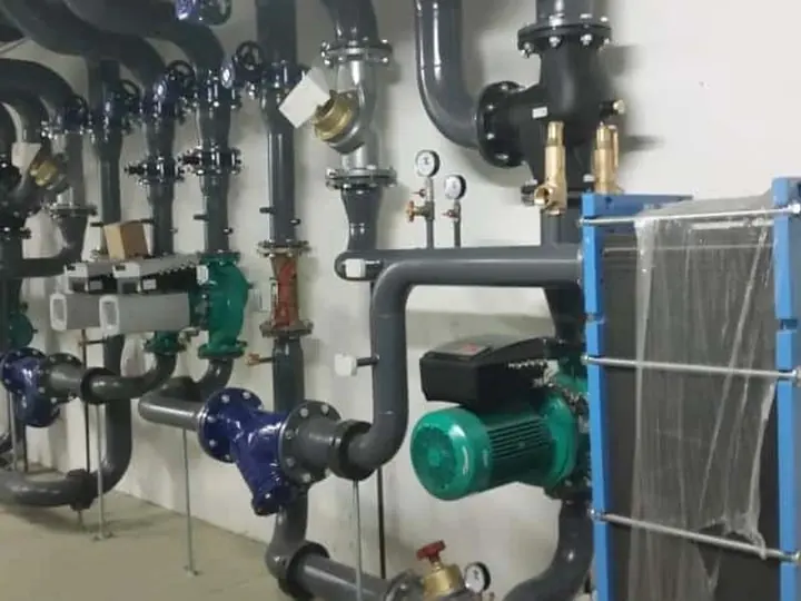 Collecteur hydraulique à brides, circulateur et échangeur à plaques dans un local technique