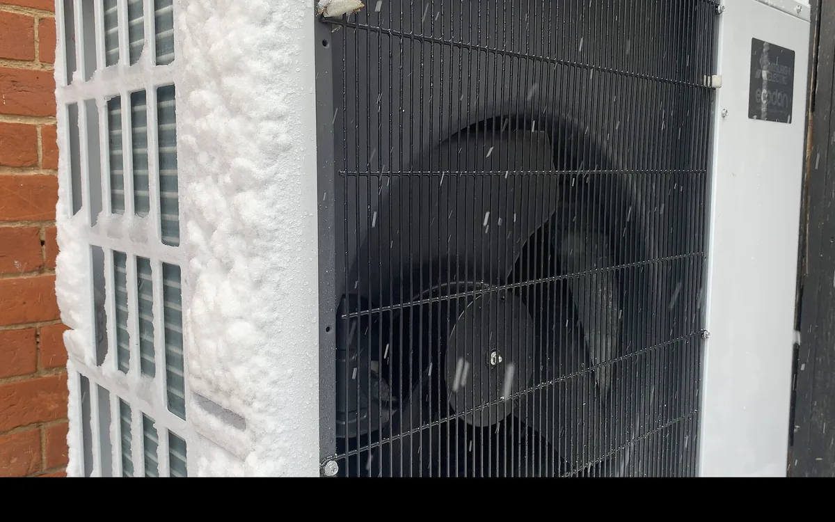 Unité extérieure en fonctionnement sous la neige, givre sur l'échangeur